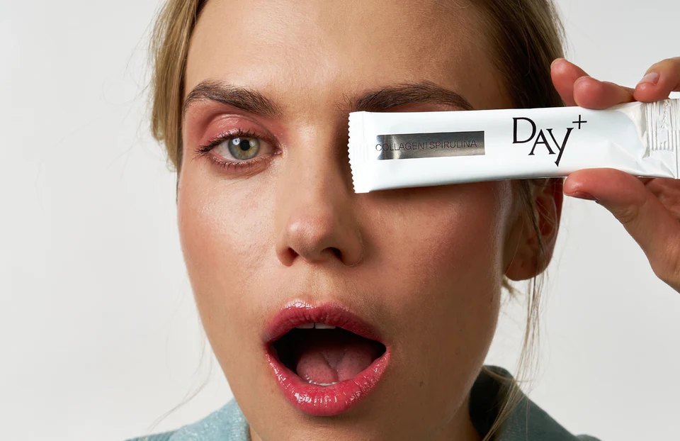 A model holds a DAY+ collagen and spirulina stick over one eye